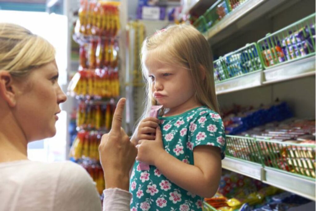 A woman scolding a young girl in a grocery store aisle.
