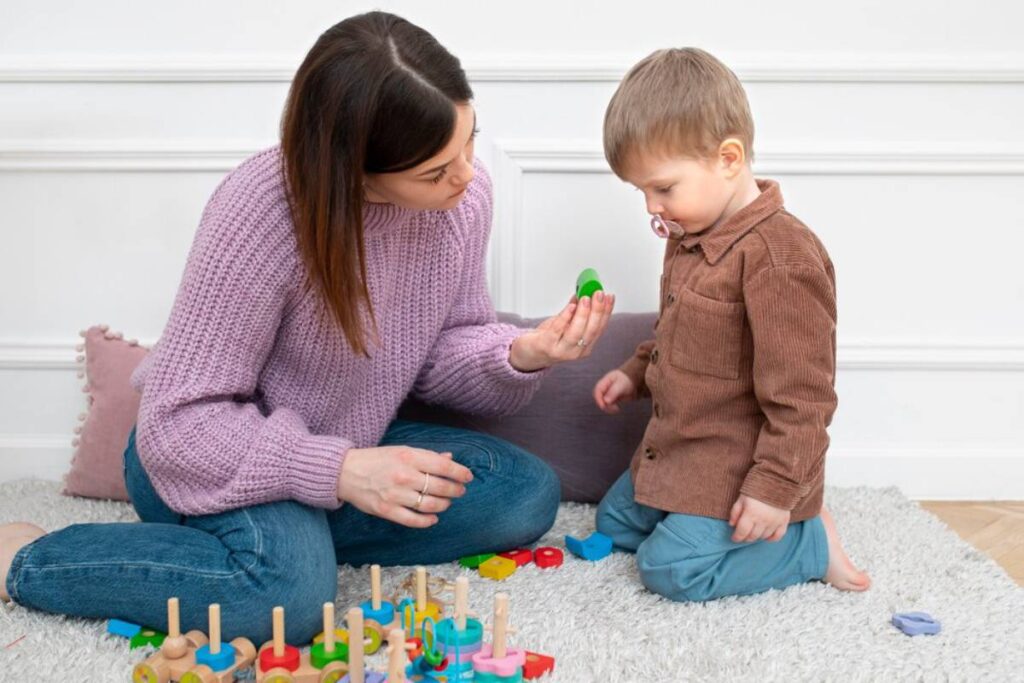 A woman and a young boy playing with colorful toys on a rug indoors.