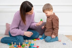 A woman and a young boy playing with colorful toys on a rug indoors.