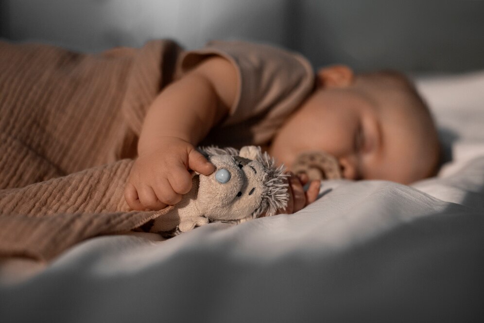A baby sleeping peacefully on a soft pillow in a dimly lit room.