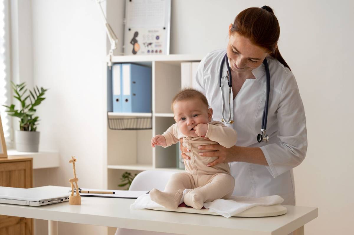 Pediatrician holding a smiling baby on an examination table in a clinic.