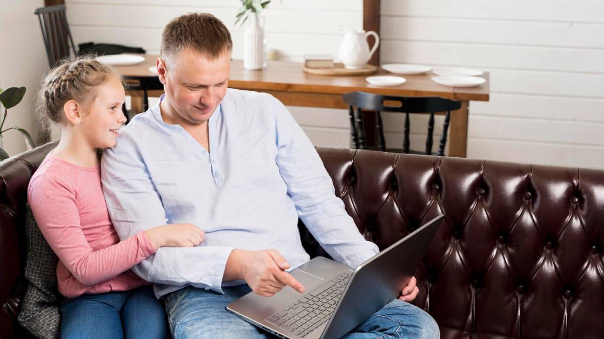 Three colleagues, two women and one man, discussing over a laptop in a bright office setting.